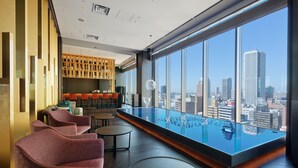A modern lounge with a glass pool, seating, and a city view. - Osaka Excel Hotel Tokyu (Osaka)