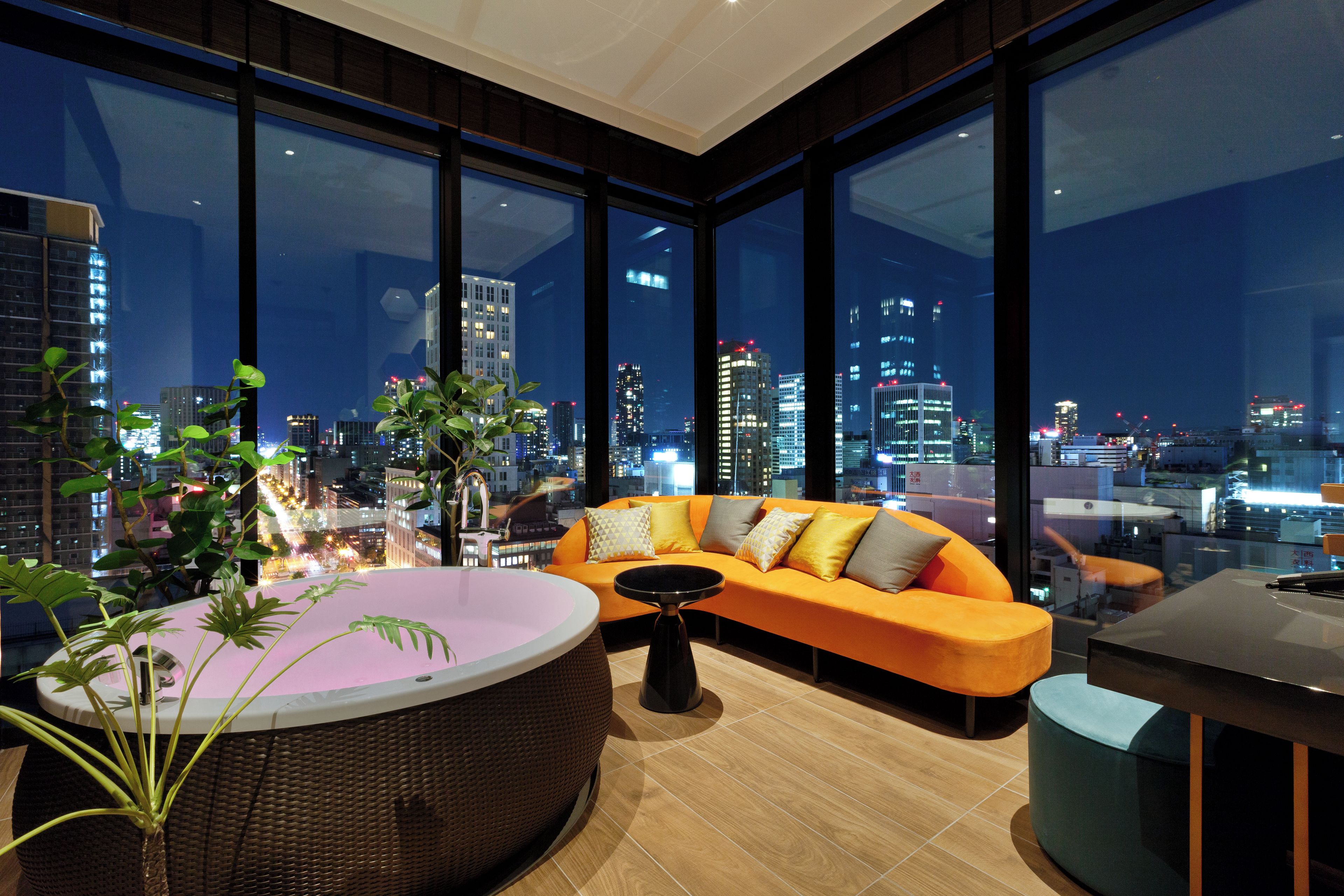 A modern living room with a large window, a sofa, a round table, and a plant.