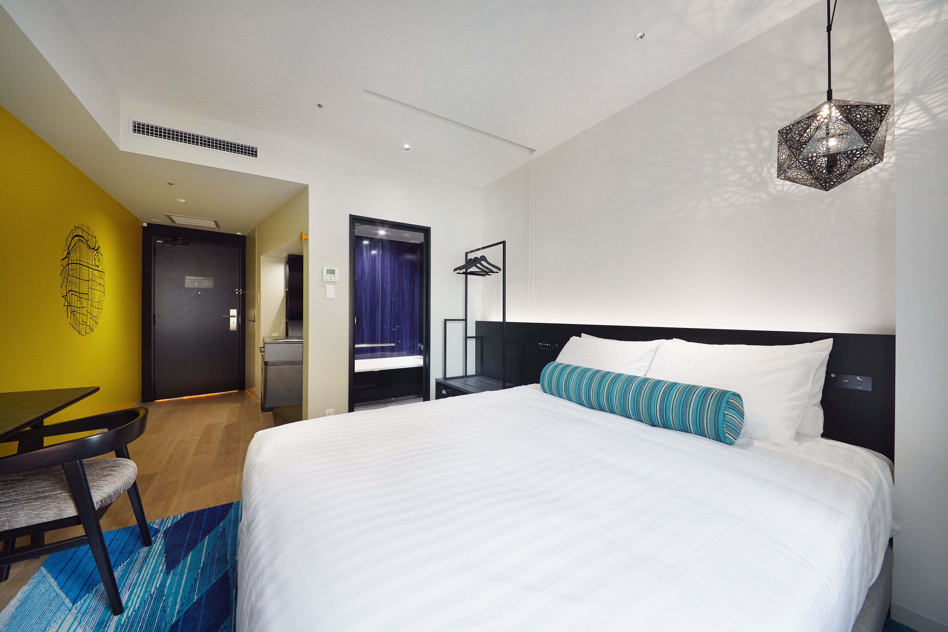 Quarto de hotel moderno com uma cama grande, uma escrivaninha e uma cadeira.