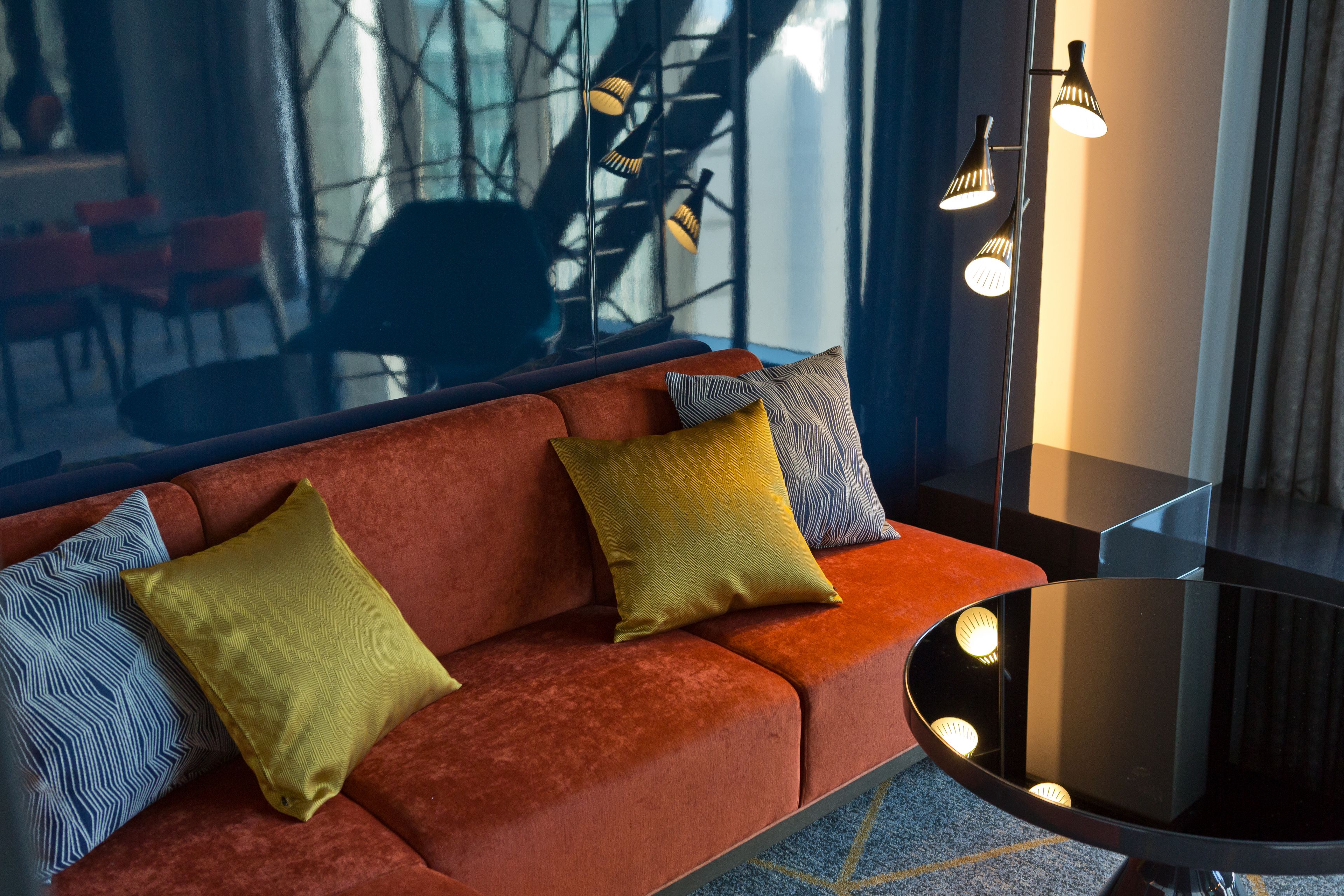 Una sala moderna con un sofá rojo, cojines estampados y una mesa de centro de vidrio.