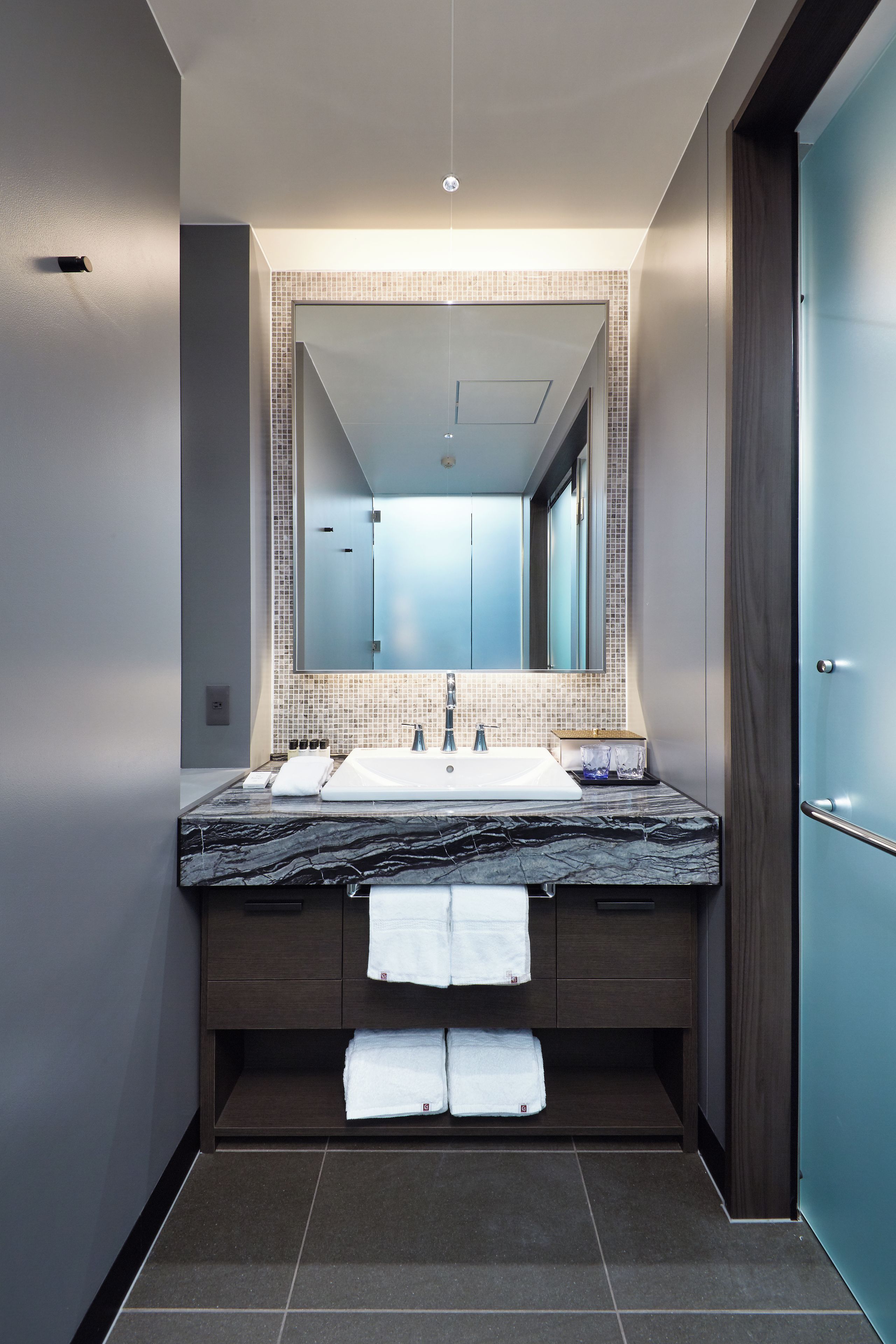 A modern bathroom with a large mirror, a sink, and a towel rack.