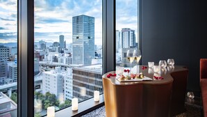 A dining table with candles and a city view through large windows. - Osaka Excel Hotel Tokyu (Osaka)
