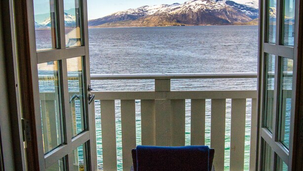 An open balcony with a view of a mountain range and a body of water.