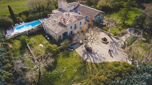 Ett stort hus med en swimmingpool, en innergård och omgivande grönska.