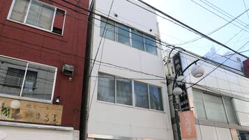 A multi-story building with a ground-floor entrance, a visible door, and a window.
