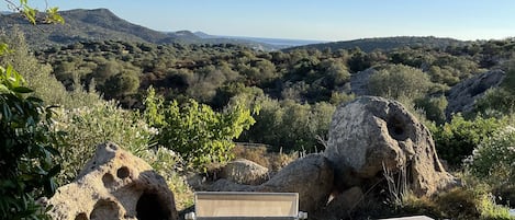 Una terraza con mesa y sillas, con vistas a un paisaje montañoso de vegetación densa.