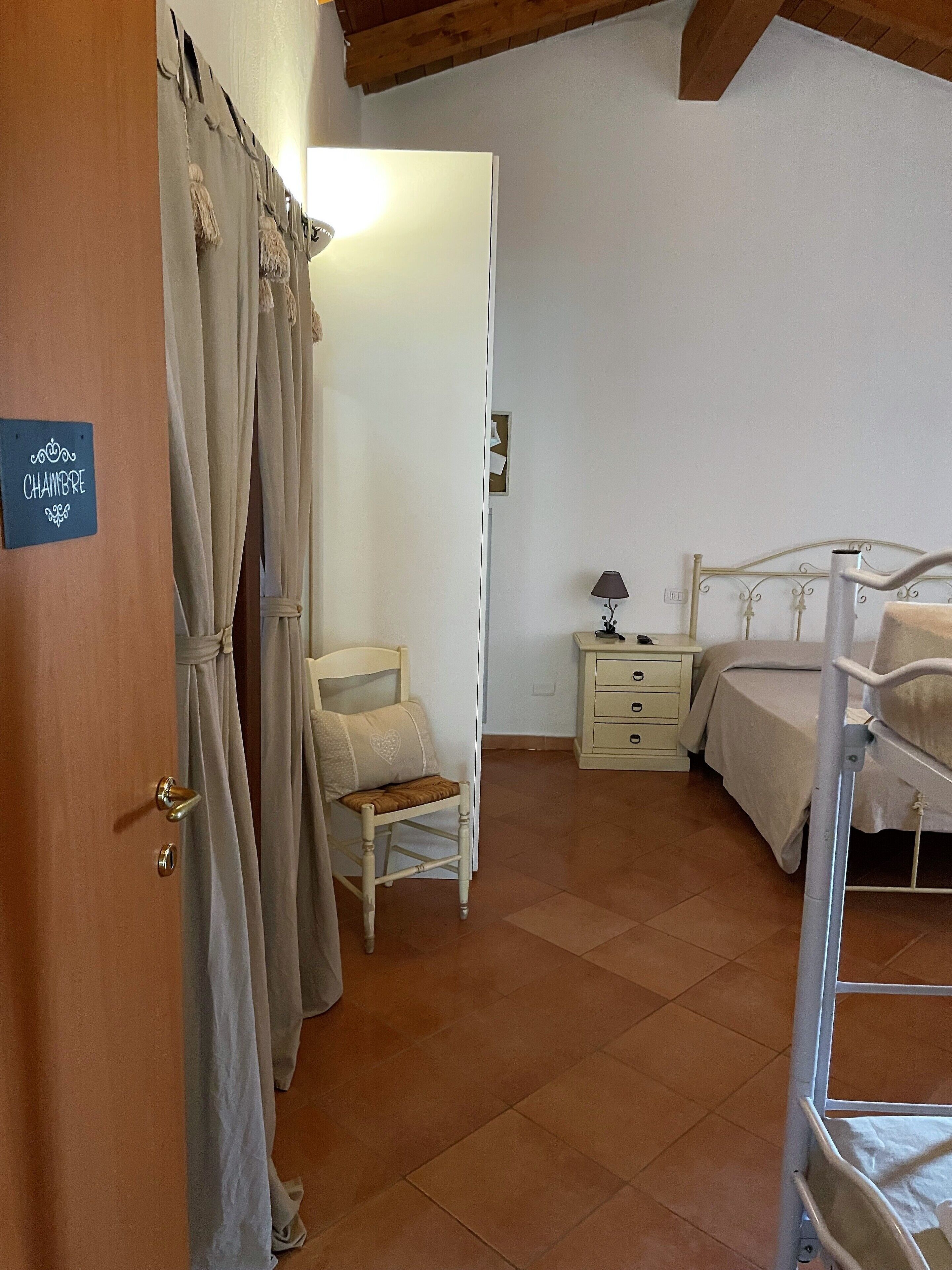 A bedroom with a bed, a chair, a nightstand, and a wardrobe.