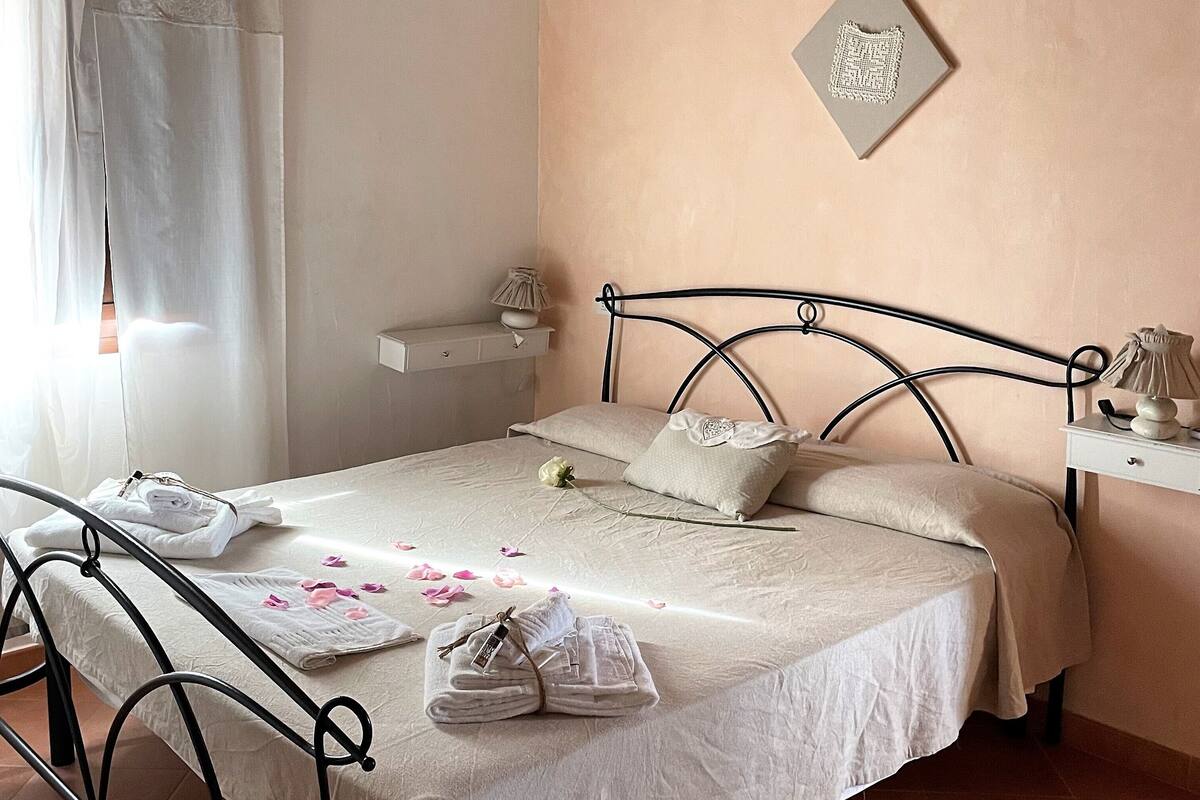 A bedroom with a bed, a bedside table, a lamp, and a wall-mounted air conditioner.