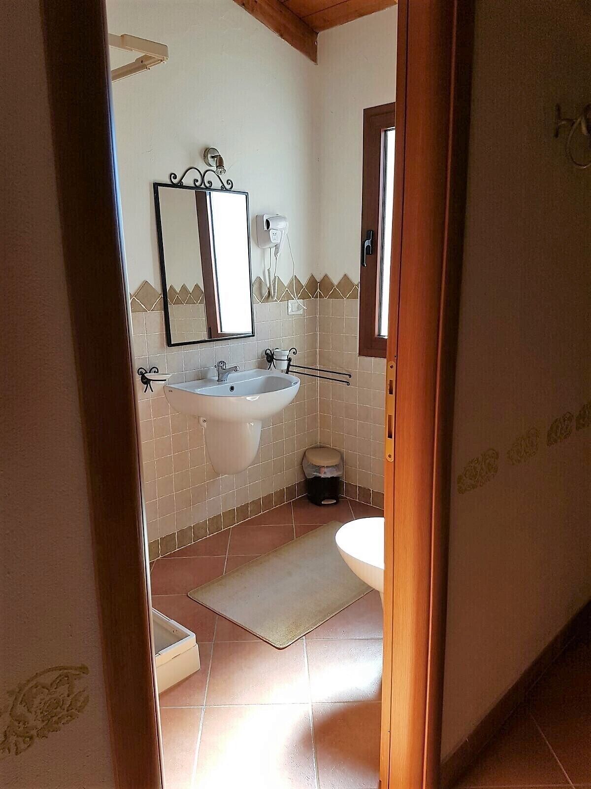A bathroom with a white sink, a mirror, and a hairdryer on the wall.