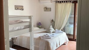 A bedroom with a wooden ceiling, a bed with white bedding, a bedside table with a lamp, and a window with curtains. - B&B Su Donnigheddu (Golfo Aranci)