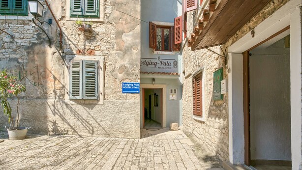A narrow cobblestone street leading to a building with a sign reading "Lodging Pula HOSTEL STYLE." - Apartment Old City 1 (Pula)