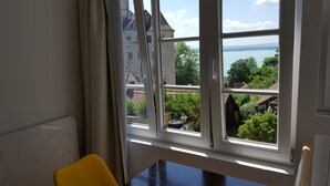 A room with a large window overlooking a body of water and a view of buildings. - Winzerhäusle Meersburg (Meersburg)