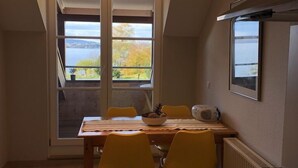 A compact kitchen with a dining area, a built-in stove, and a view of a lake through a large window. - Winzerhäusle Meersburg (Meersburg)