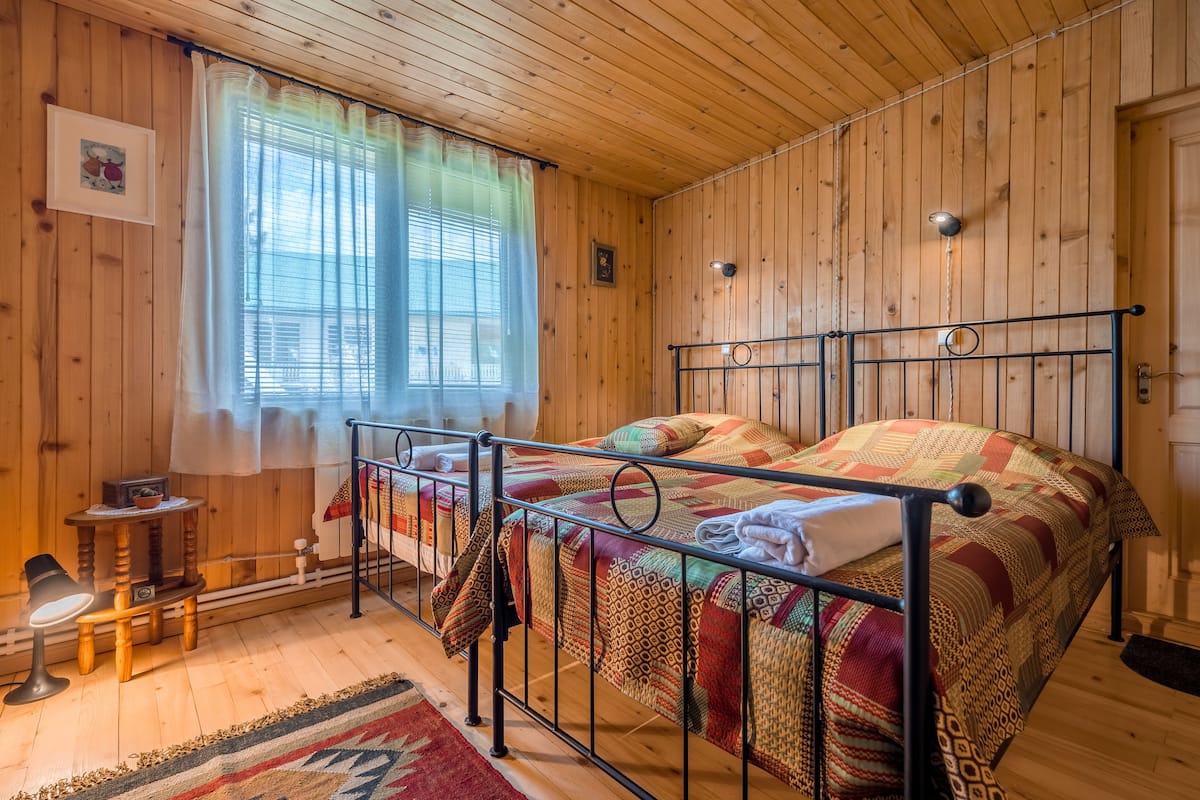 Una habitació amb panells de fusta, un llit, una taula petita i una cadira.