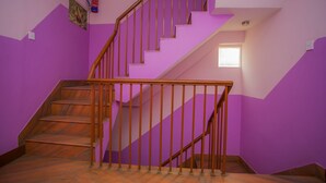 Un escalier avec des marches en bois et une rampe en bois, dans une pièce aux murs violets.
