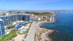 A coastal hotel with multiple high-rise buildings, a beach, and a clear view of the sea.