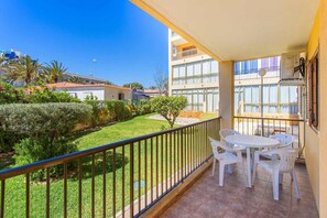 A balcony with a view of a garden and neighboring buildings.