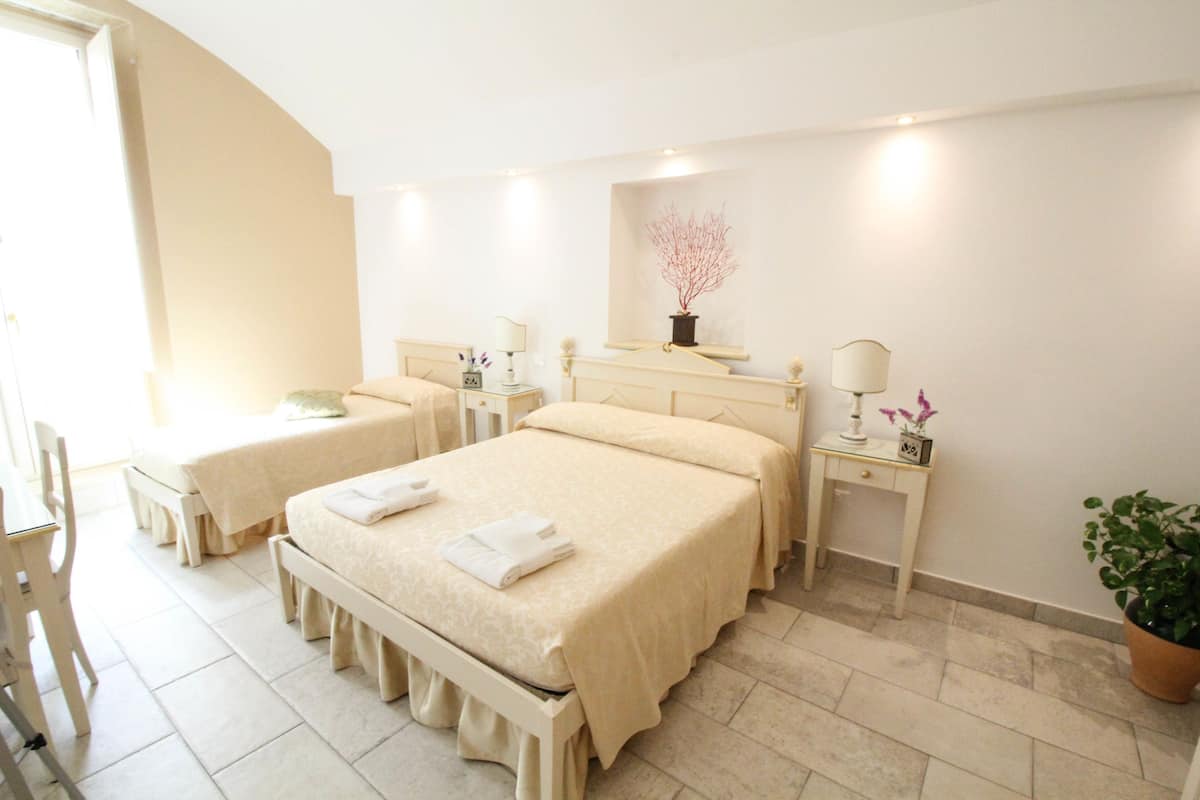 Ein Hotelzimmer mit zwei Betten, einer Sitzecke, einem kleinen Tisch mit Lampe und einem Blumentopf.