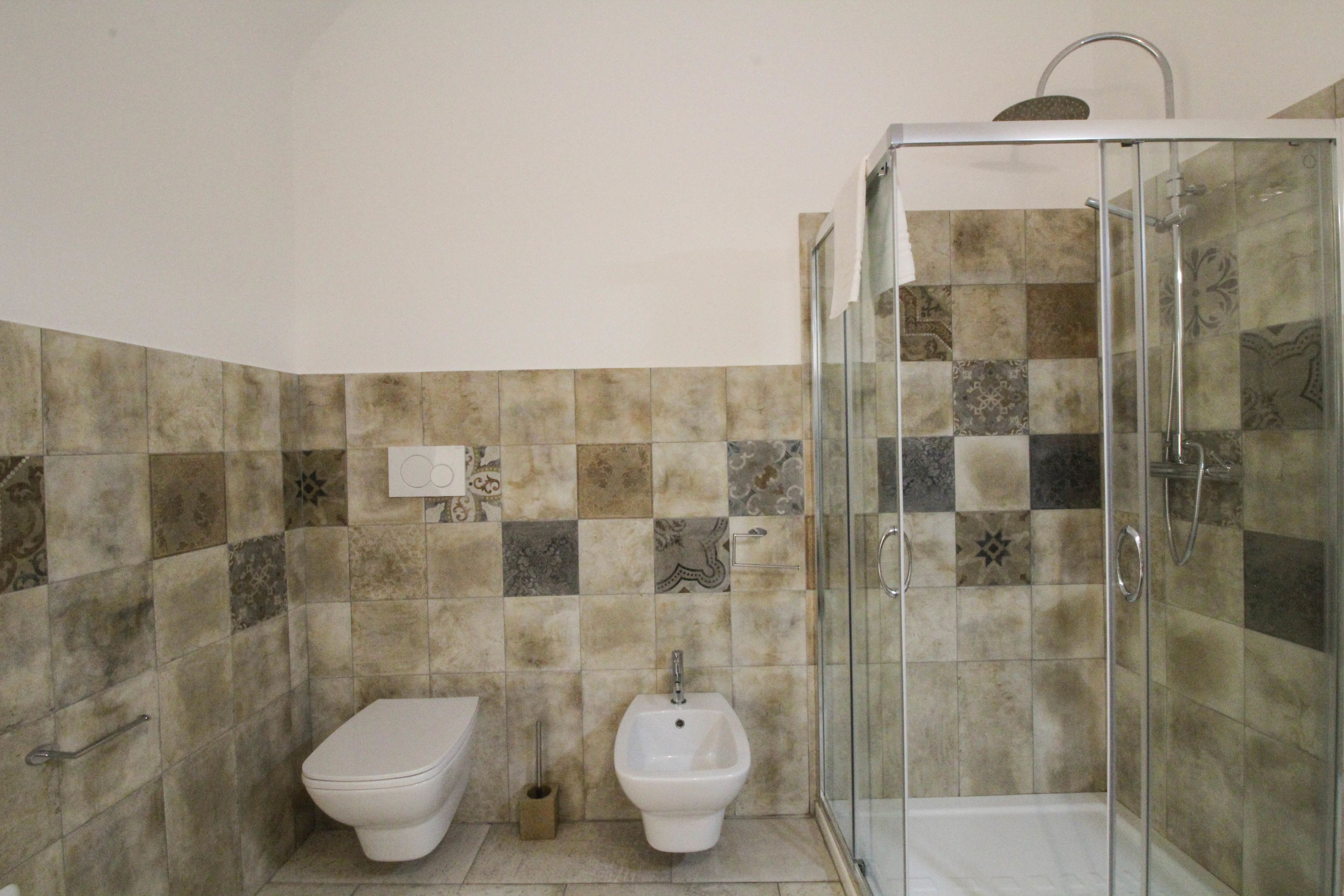 Une salle de bain comprenant des toilettes, un bidet et une cabine de douche en verre.