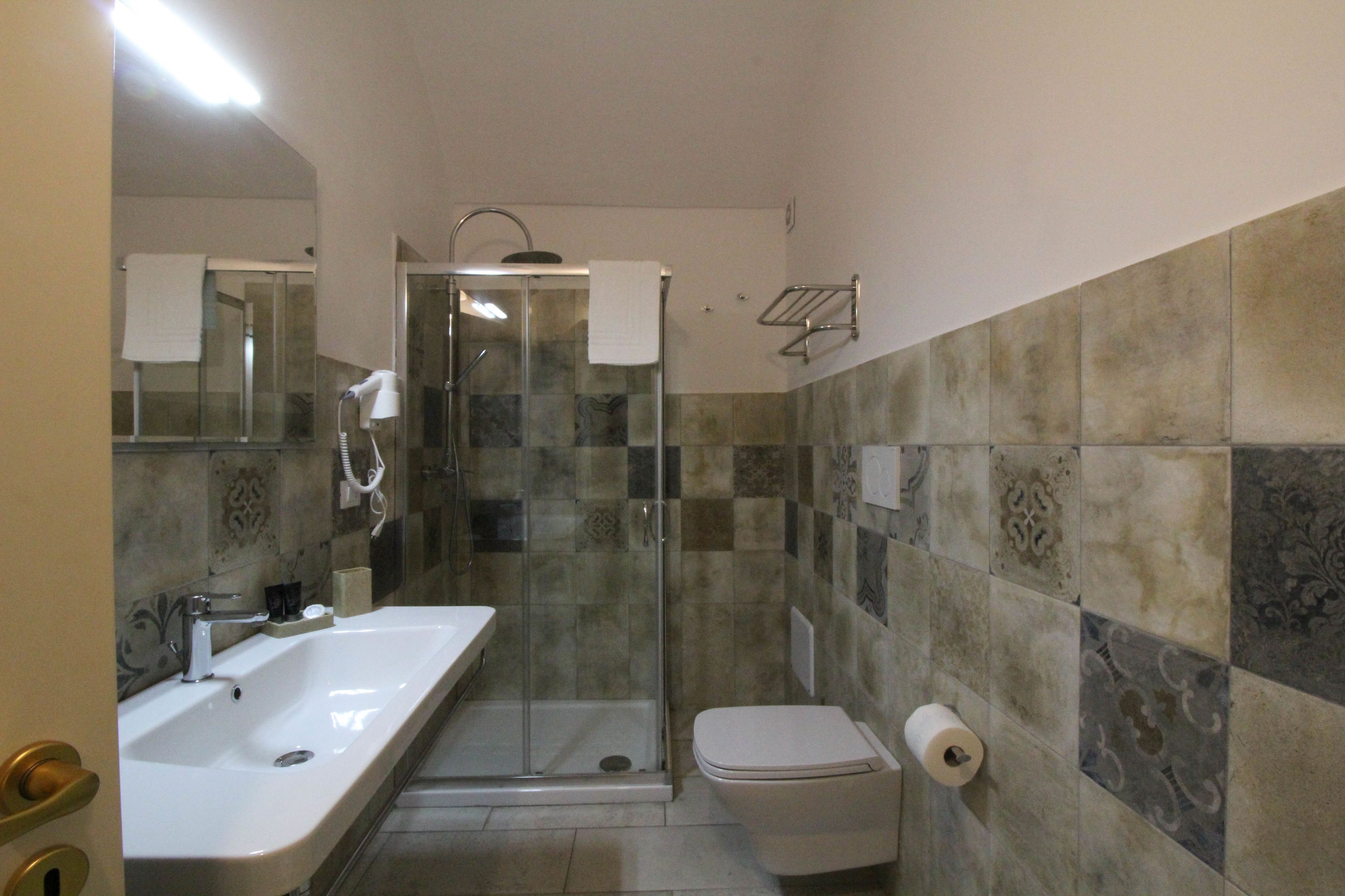 A bathroom with a glass-enclosed shower, a white sink, and a toilet.
