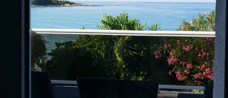 A balcony with chairs, a view of the sea, and a tiled floor.