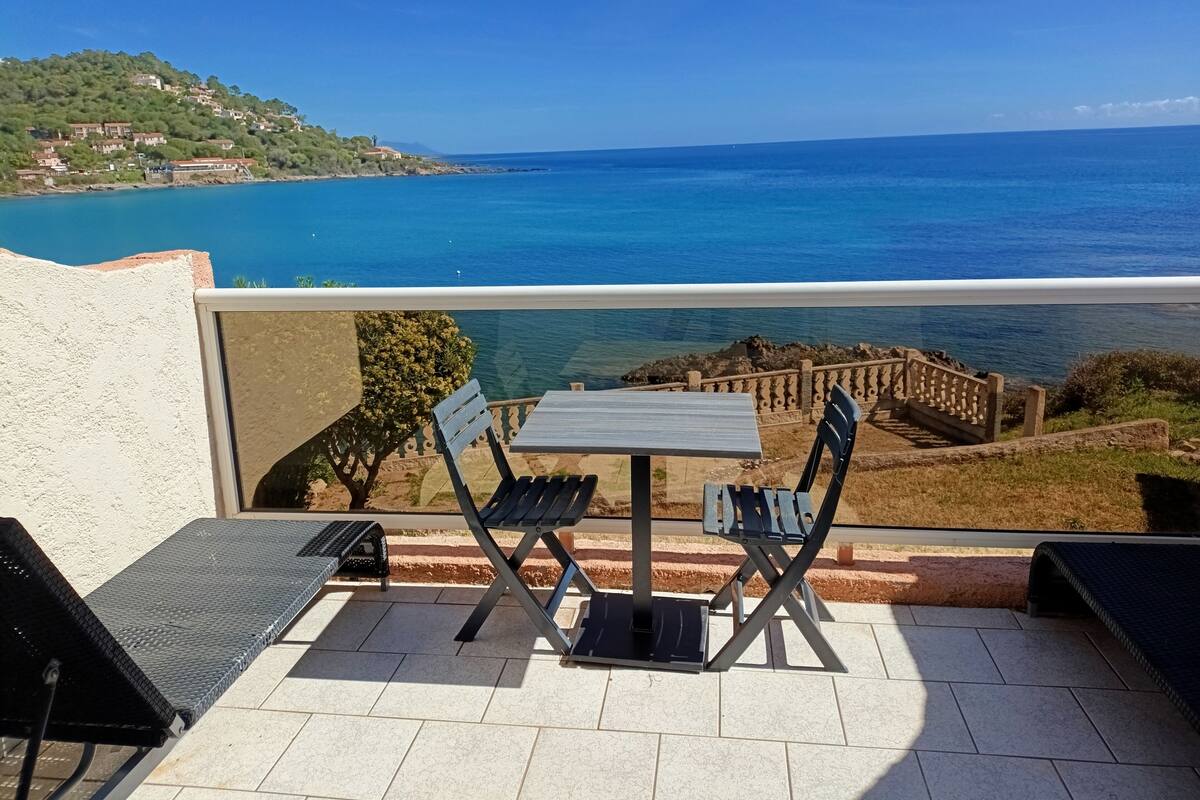 A terrace with a table and chairs overlooking a coastal view.