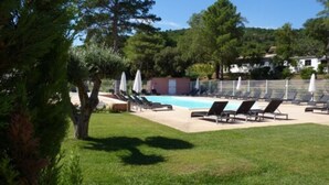 A pool area with sun loungers and umbrellas, surrounded by trees and a hilly landscape. - Résidence les Pavillons du Golfe (Conca)