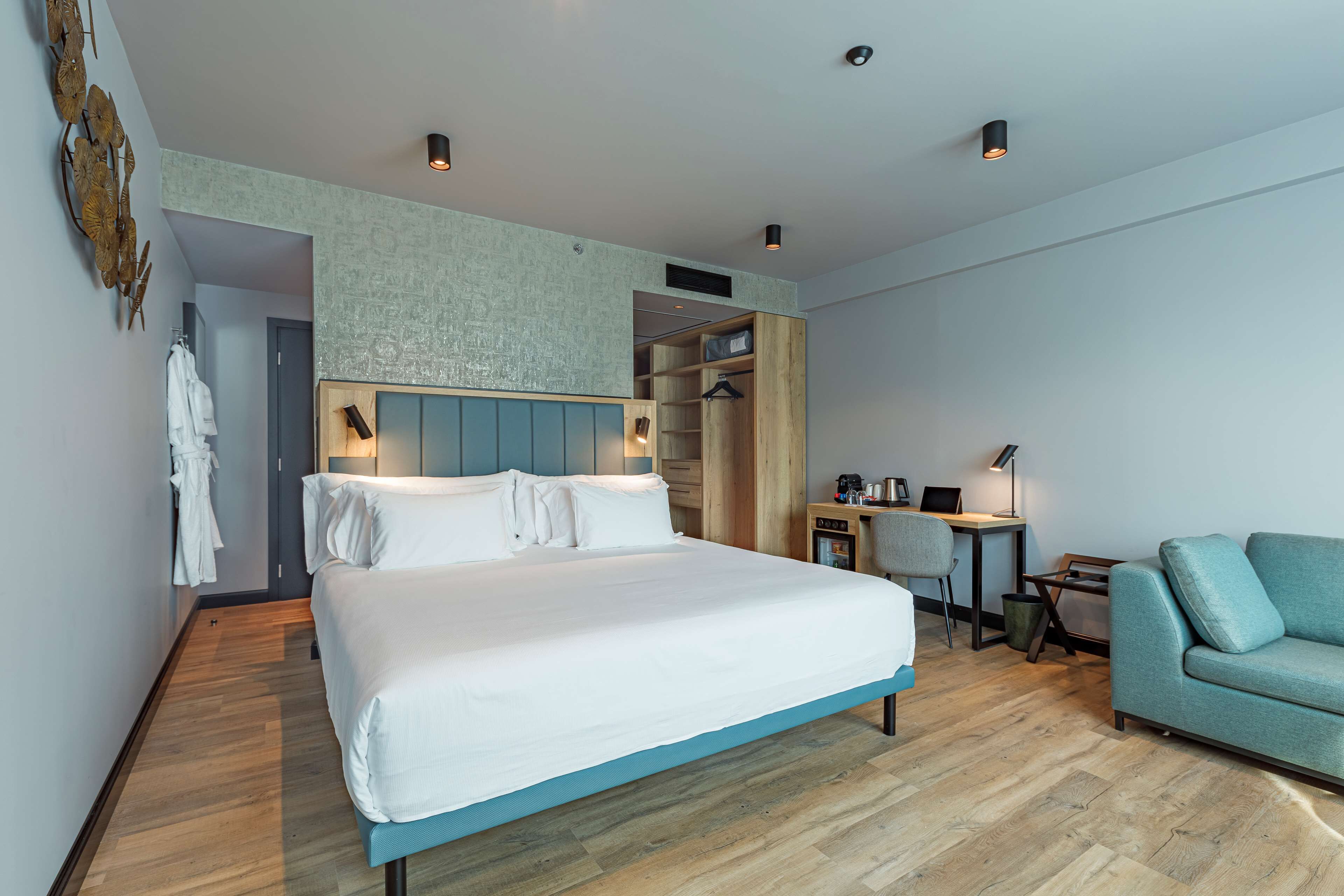 Una habitación de hotel moderna con una cama grande, un escritorio con silla, un armario y un sofá.