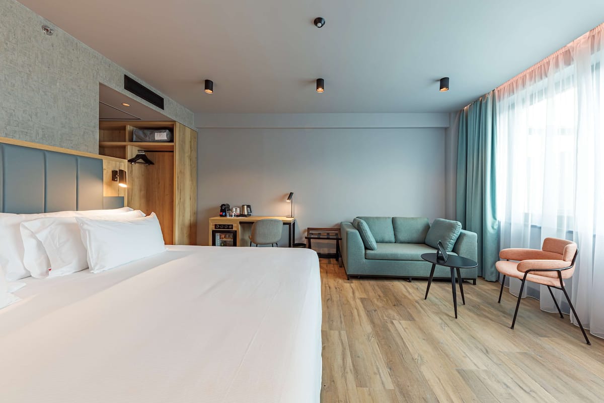 Une chambre d’hôtel avec un grand lit, un canapé, un bureau avec une chaise et une petite table.