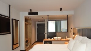 Habitación de hotel moderna con una cama grande, una mesita de noche con lavamanos, un espejo y un armario.