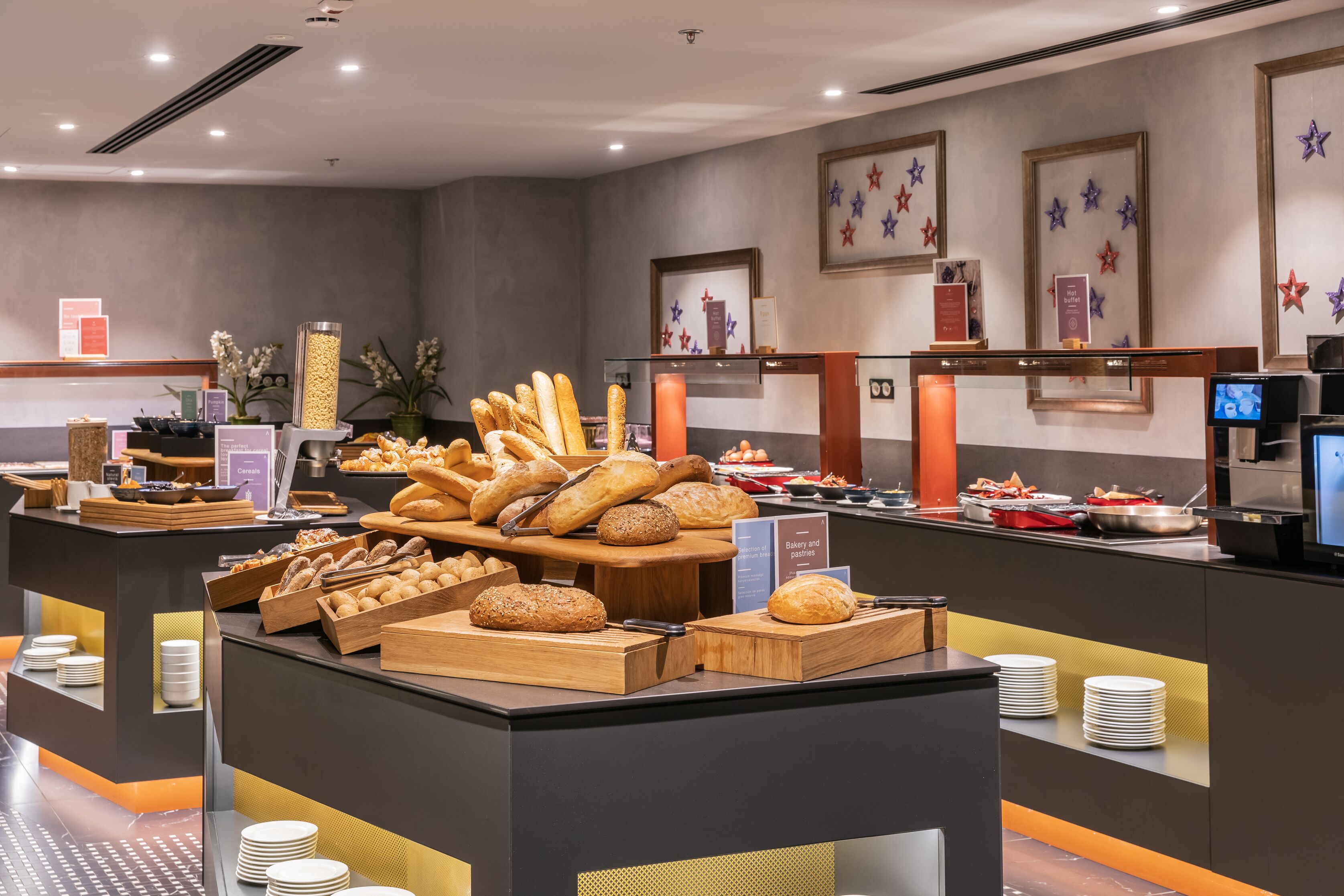Un'area buffet con diversi tipi di pane e pasticceria esposti su assi e vassoi di legno.