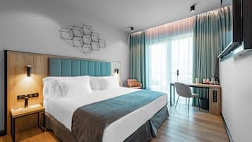 A modern hotel room with a large bed, a desk, and a chair.