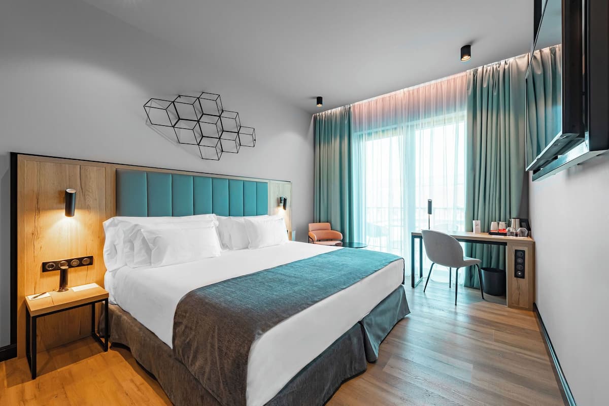 Une chambre d’hôtel moderne équipée d’un grand lit, d’un bureau, d’une chaise et d’une télévision.