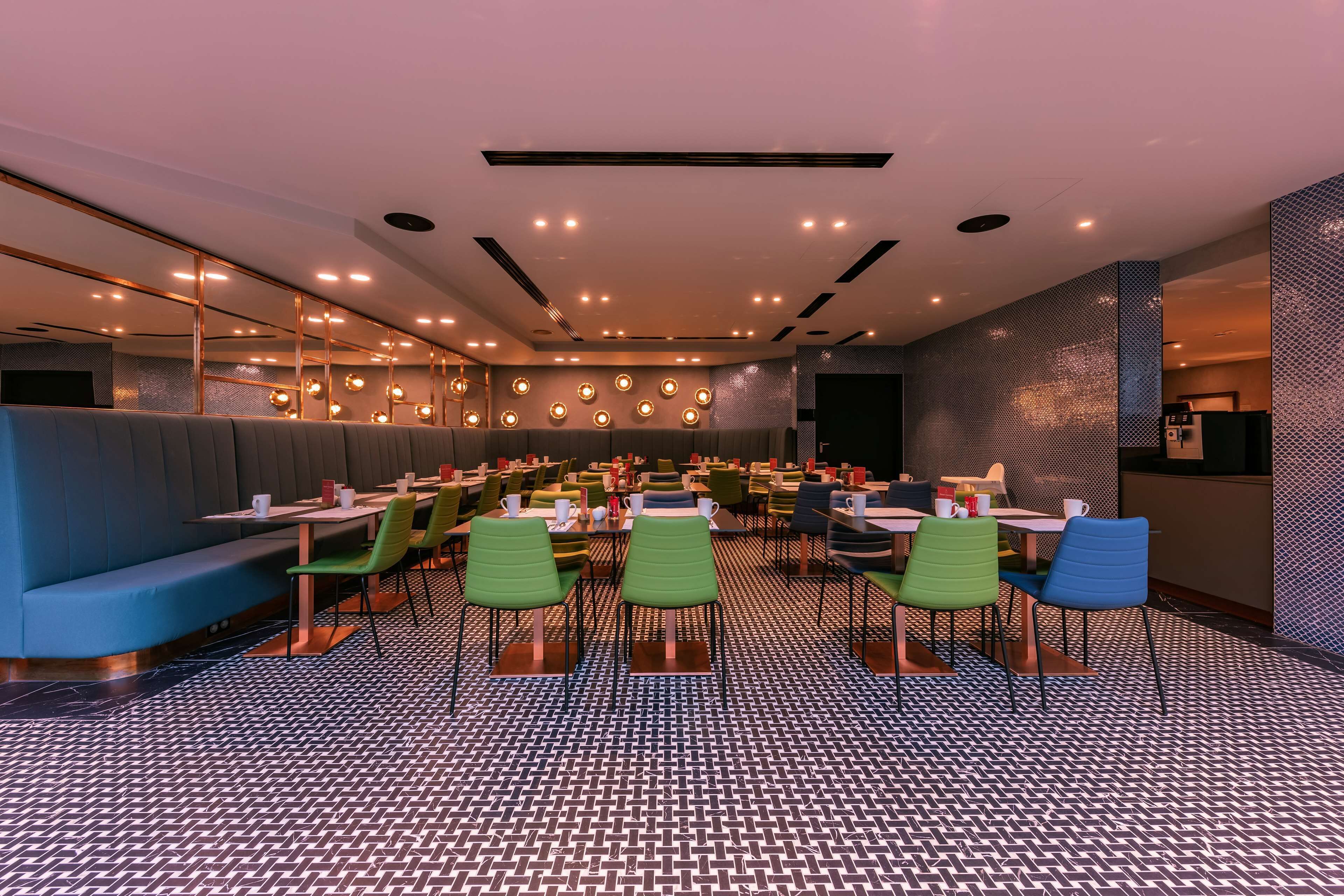 A modern restaurant with booths and tables, patterned flooring, and ambient lighting.