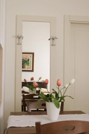 A dining area with a table set for two, a white tablecloth, and a vase with flowers. - Fra' iMari (Gallipoli)