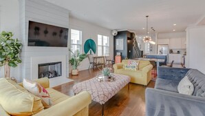 Un amplio salón con chimenea, un comedor y una cocina al fondo.