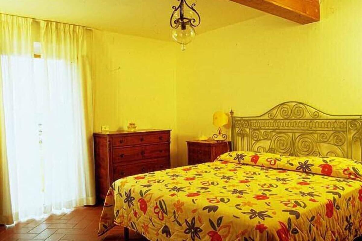 A bedroom with a bed, a nightstand, a dresser, and a chandelier.