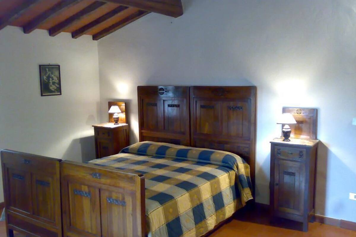 A bedroom with a wooden bed, two bedside tables with lamps, and a wooden wardrobe.