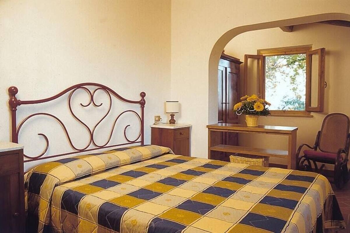 A bedroom with a bed, desk, chair, and a window with a view.