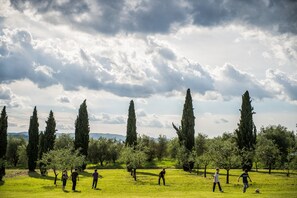Un parque con altos cipreses y un campo cubierto de césped.