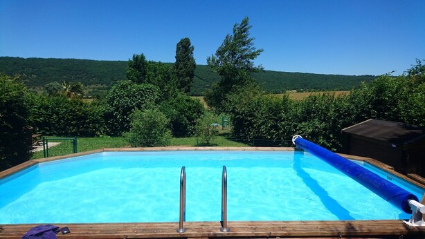 A rectangular swimming pool with clear blue water, surrounded by a wooden deck.