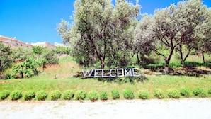 A welcome sign surrounded by trees and greenery. - Villa Green Garden (Sarandë)