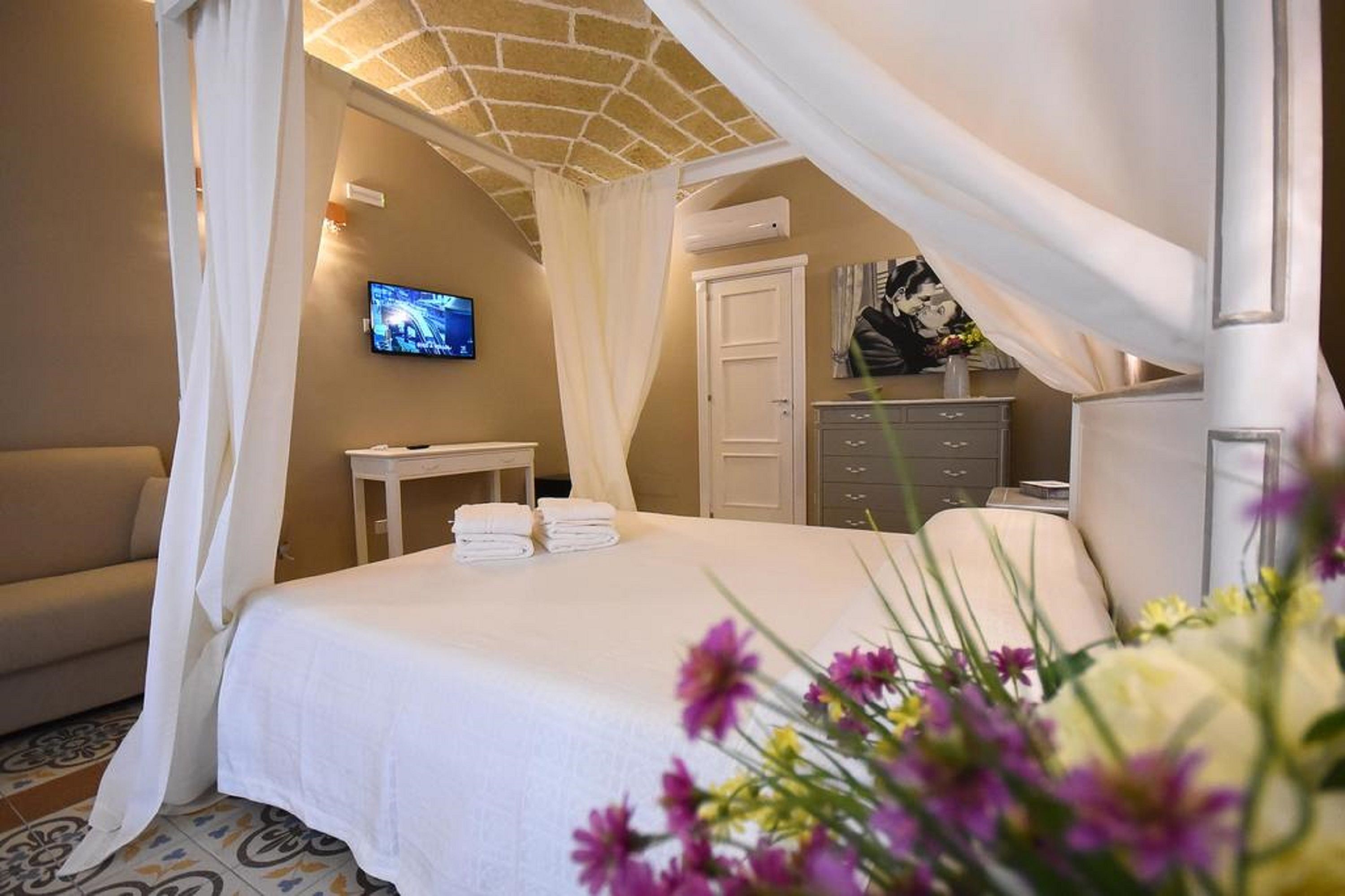 Ein Schlafzimmer mit Bett, Fernseher, Schreibtisch und Kleiderschrank.