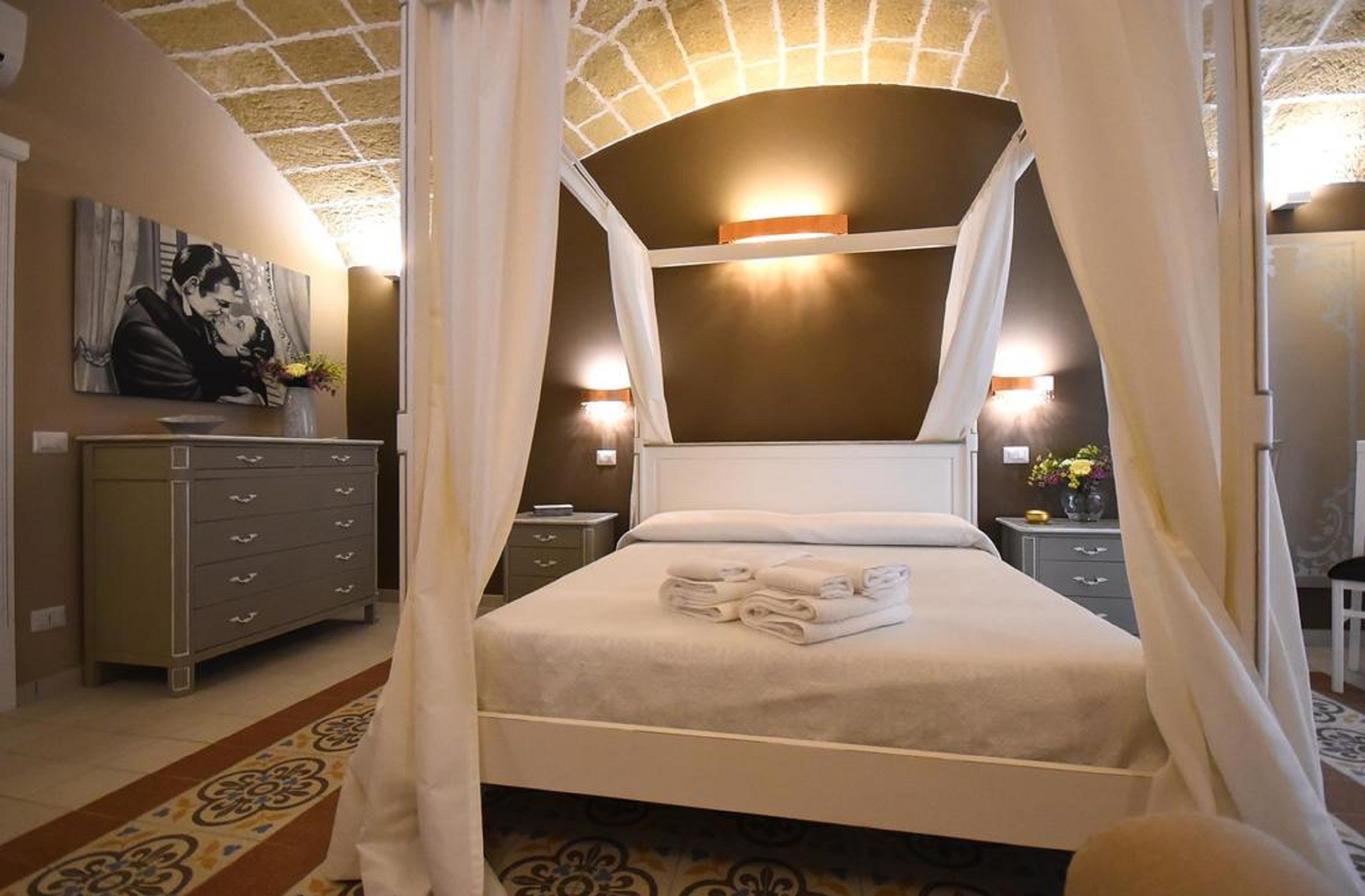 Un dormitorio con cama a dosel, cómoda, mesita de noche y un cuadro en la pared.