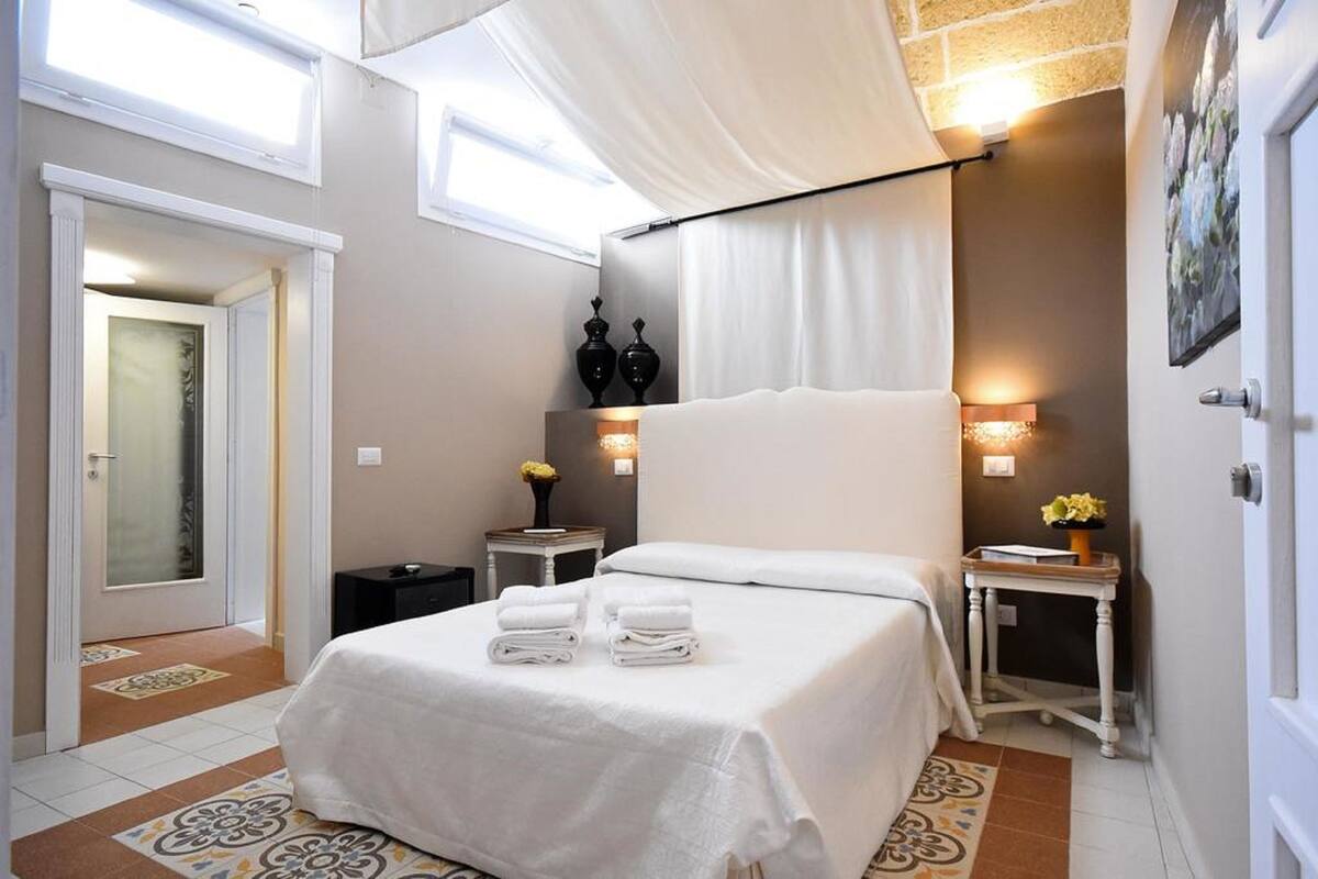 Una habitación de hotel con una cama, dos mesitas de noche y una ventana con cortinas.