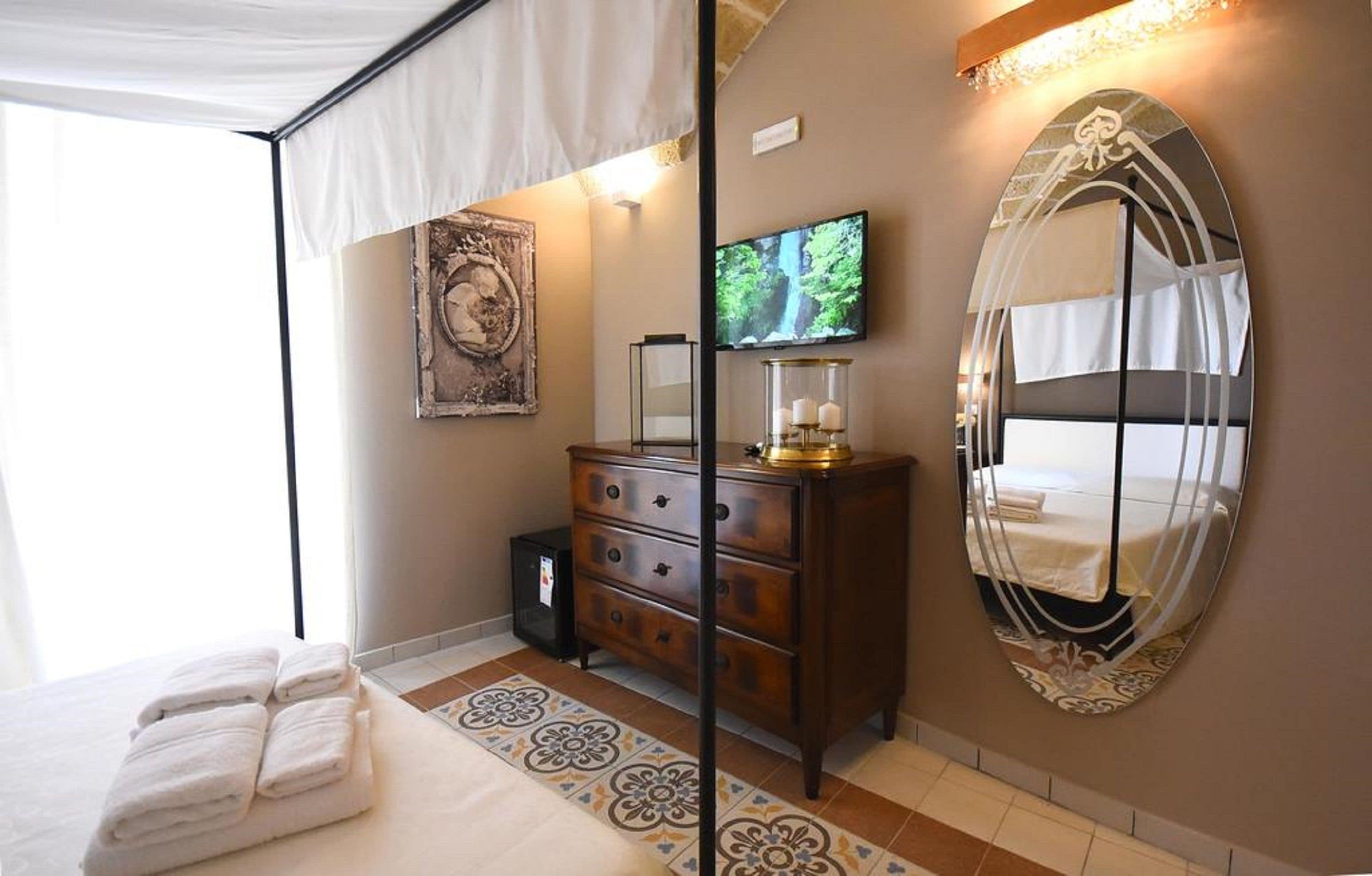 A bedroom with a bed, a dresser, a television, and a large mirror.