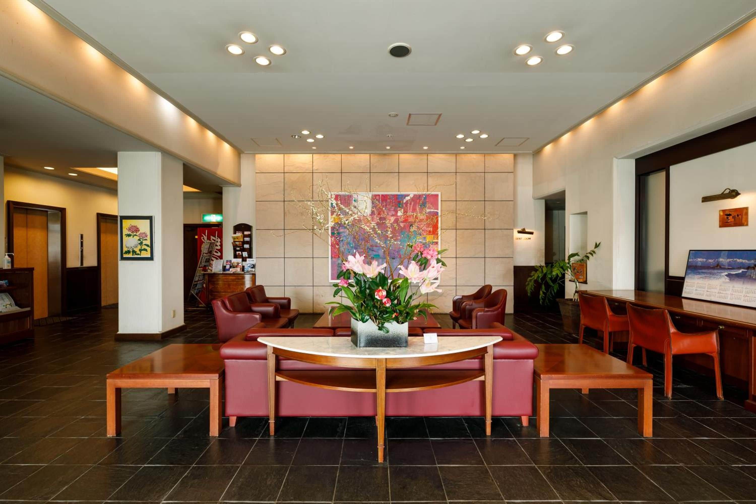 A hotel lobby with a reception desk, seating area, and a large abstract painting.
