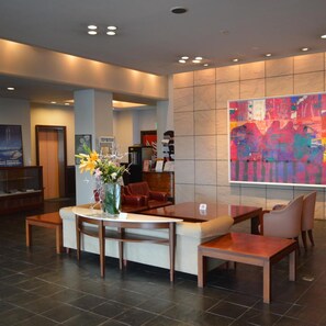 A hotel lobby with a reception desk, seating area, and a large abstract painting on the wall. - Fukuno Town Hotel Amieux (Nanto)