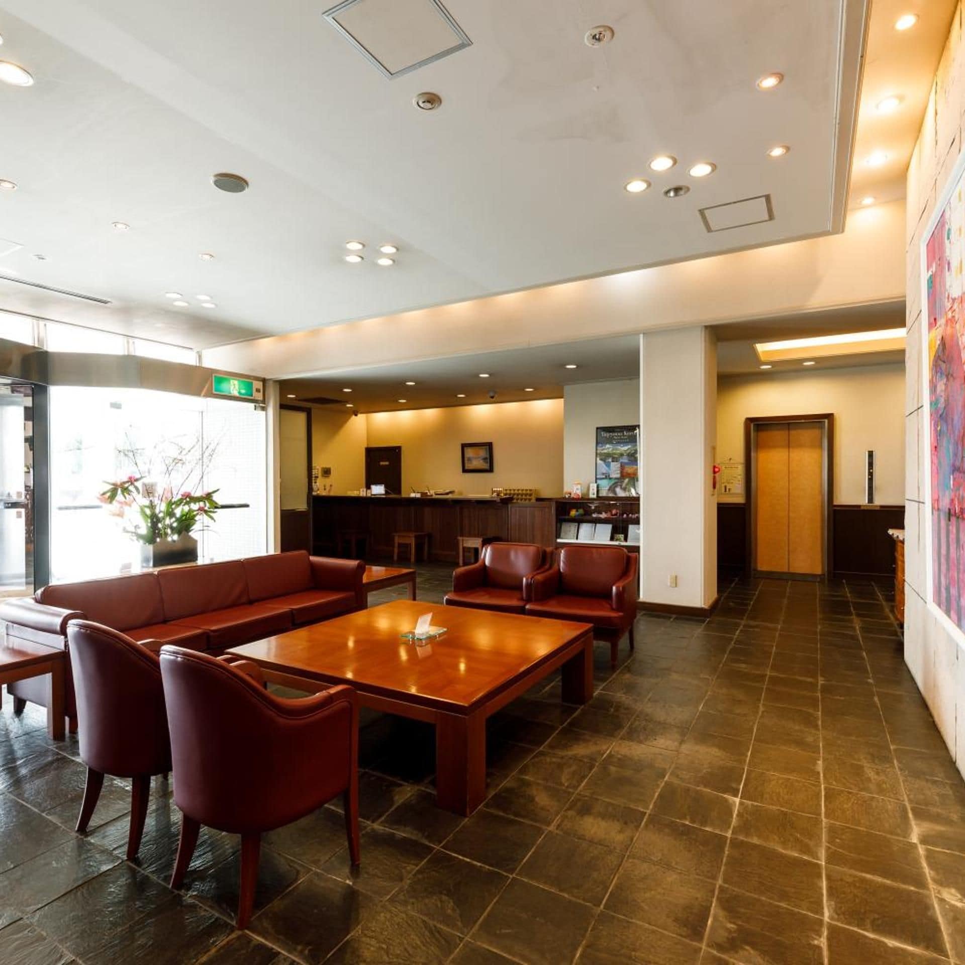 A spacious lobby with a reception desk, seating area, and a large window.