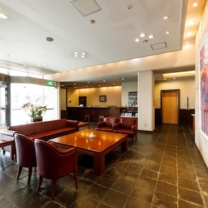 A spacious lobby with a reception desk, seating area, and a large window.
